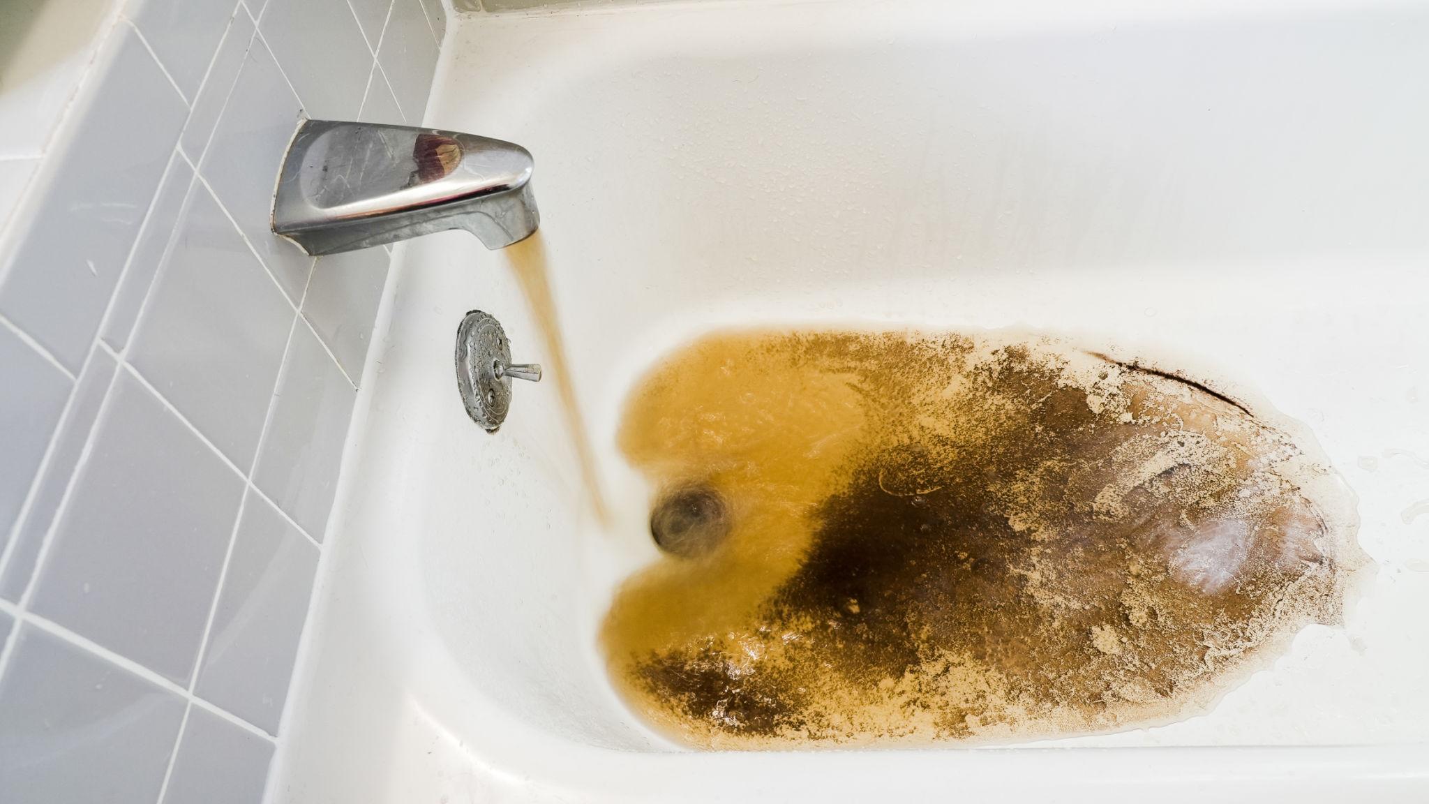 Rusty brown water flowing from bathtub faucet